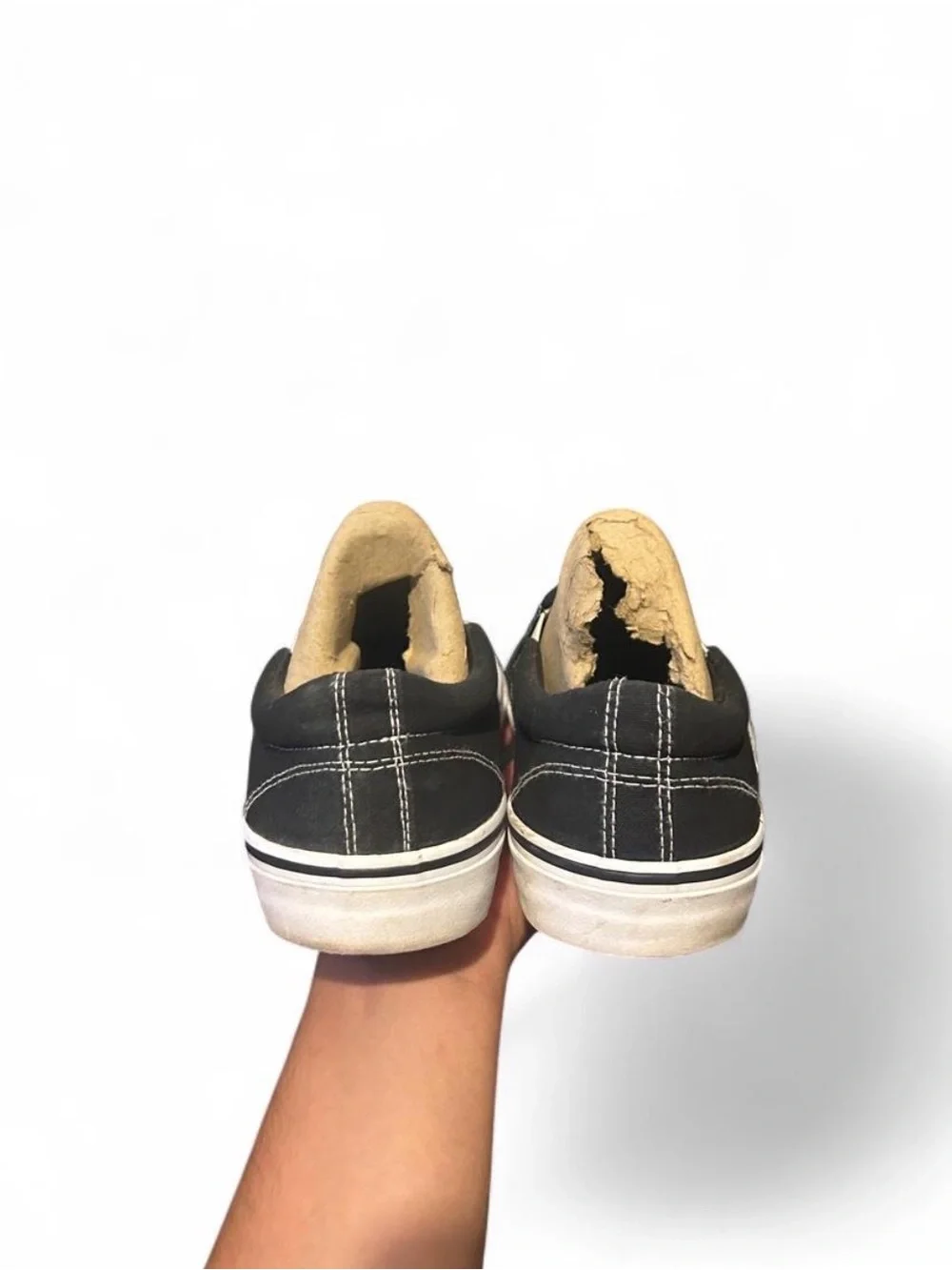 Black slip-on sneakers with white sole and white stitching